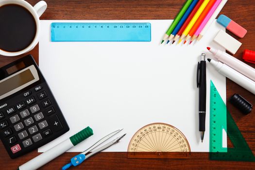 Desk with sheet of paper and stationery objects seen from above