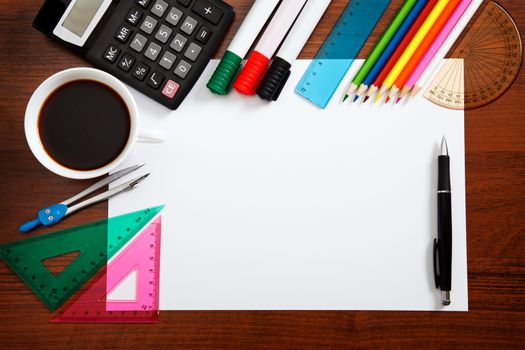 Desk with sheet of paper and stationery objects seen from above