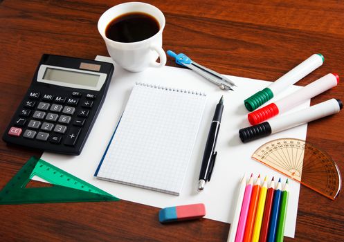 Desk with sheet of paper and stationery objects seen from above