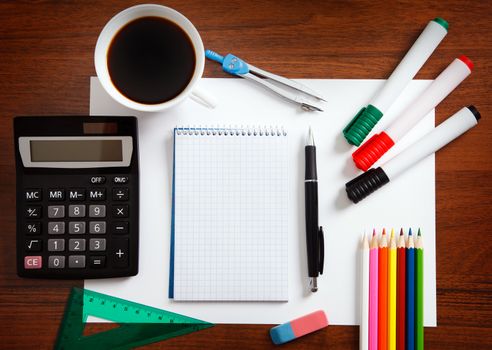 Desk with sheet of paper and stationery objects seen from above