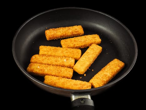Crumbed fish fingers in fry pan, isolated on black