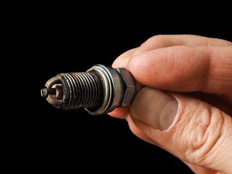 Closeup of a worn spark plug held by caucasian male fingers