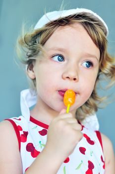 sweet blonde girl with lollipop in summer time