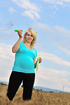 pregnant woman with soap bubbles standing in field