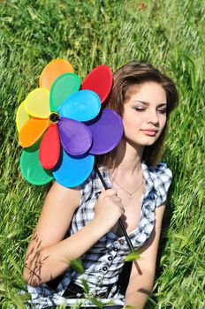 girl with windmill sitting in the green grass