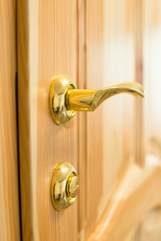 Golden door handle and lock on the new wooden door in the joiner's shop