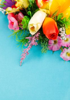 artificial flowers on blue background with place for label