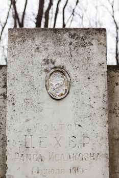 Old gravestone with damaged portrait of the buried person.