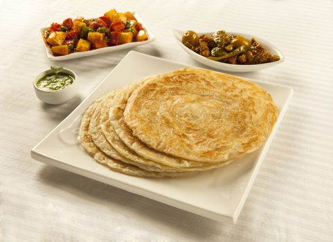 Paratha served with mixed vegetables, chutney and pickles