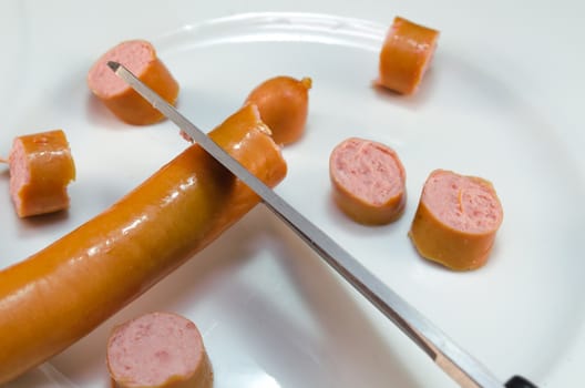 Vienna sausages cut with scissors.
Sausage pieces on white plate.
