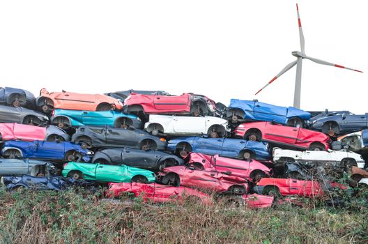 Scrap cars, scrap cars on a stack in the background a wind turbine for energy.