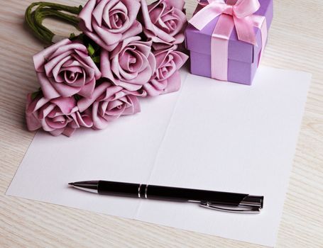 blank card with a pen, purple roses and purple gift box