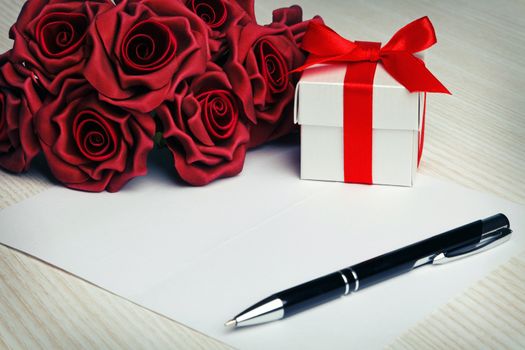blank greeting  card with a pen,red roses and white gift box