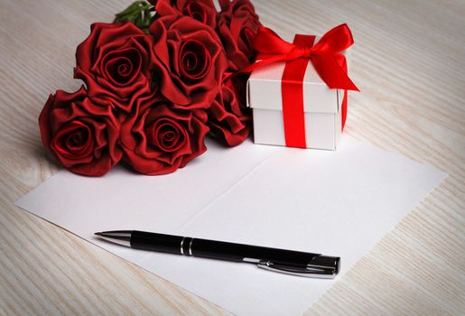 blank greeting  card with a pen,red roses and white gift box