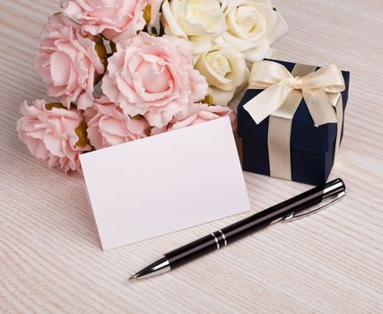 Greeting card with pen, blue gift box, pink and white roses 