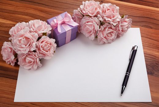 Greeting blank card with pen, pink roses and purple gift box