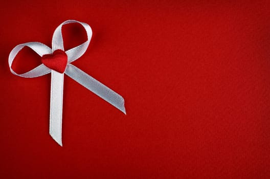 White bow with heart on a red background, place for text