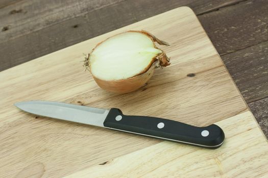 Onion on a wooden chopping board with knife