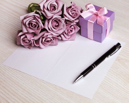 blank card with a pen, purple roses and purple gift box