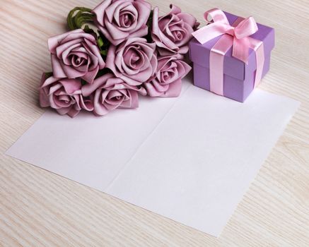 blank card with a pen, purple roses and purple gift box