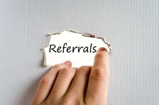 Hand and text Referrals on the cardboard background - business concept