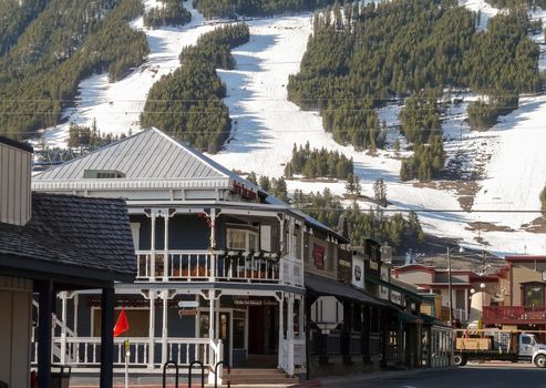 Jackson Hole, WY, USA - May 13, 2008: Ski slopes in Jackson Hole with snow remnants, in front vintage houses.