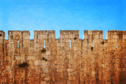 Defensive wall of the ancient holy Jerusalem, lit by the bright sun. Photo in old color image style.