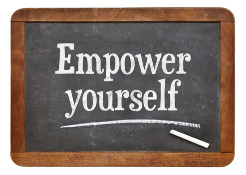Empower yourself motivational phrase - text on an isolated  vintage slate blackboard
