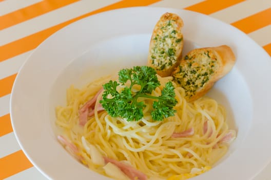 Spaghetti Carbonara with bacon and garlic bread on dish