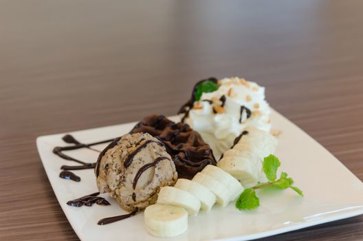 ice cream , banana , chocolate waffles with chocolate sauce and whipping cream
