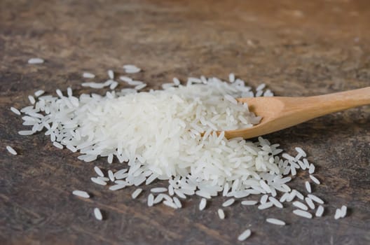 white rice  grains with wooden spoon on wooden table
