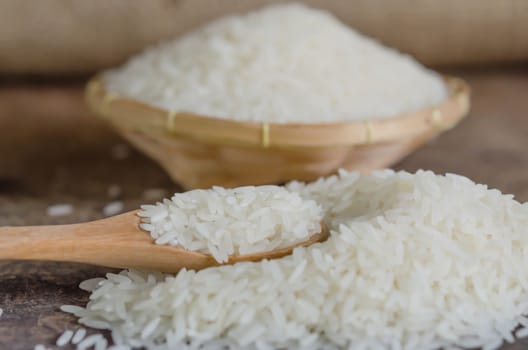 white rice  grains with wooden spoon on wooden table
