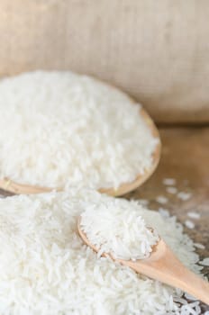 white rice  grains with wooden spoon on wooden table