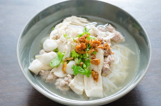Bowl of Vietnamese pho noodle soup with sausage served with onions, scallions and cilantro