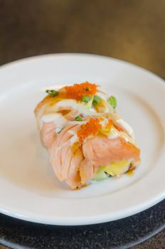 Salmon roll sushi with shrimp egg on top in white dish