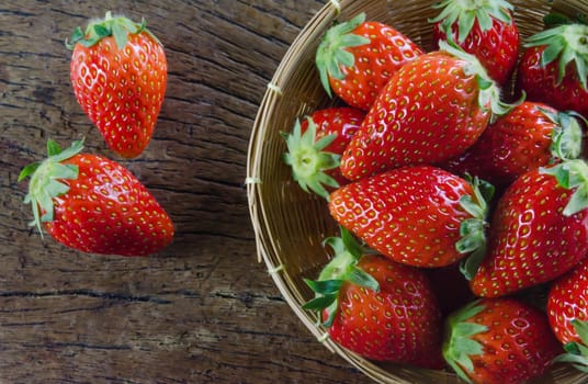 Fresh strawberries on basket , over old wooden background