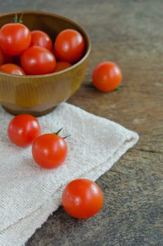 Red cherry tomatoes  on a textured  wooden background