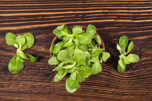 Fresh green corn salad in wooden bowl on old wooden vintage background, top view. Fresh salad, rustic vintage country style image.