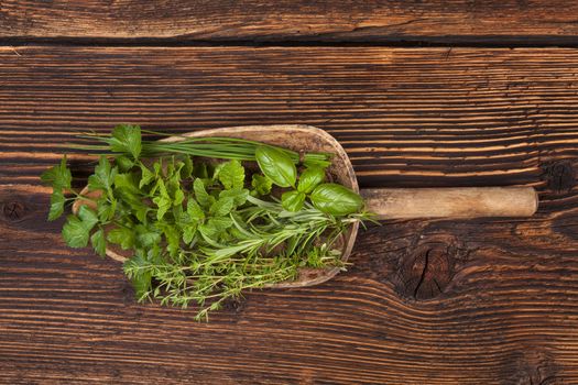 Various aromatic culinary herbs. Thyme, marjoram, basil, mint, chives and parsley herbs on wooden spoon on old brown wooden background. Rustic, vintage, natural, country style images.