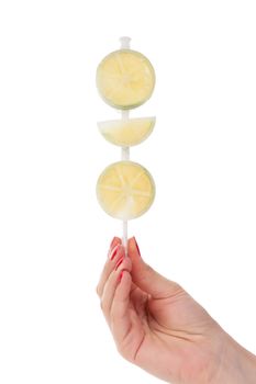 Female hand holding frozen lime fruit popslice isolated on white background. Healthy summer eating. Healthy summer eating. 
