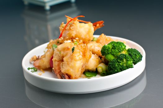 Thai style crispy honey shrimp dish presented beautifully on a round white plate with copy space above.