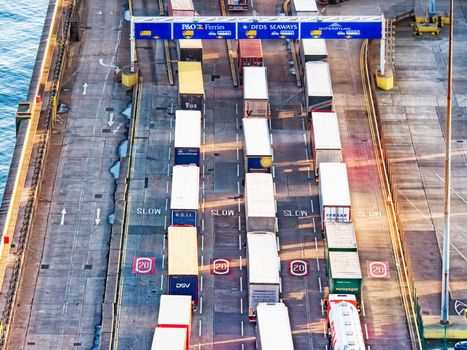 Line of trucks in sea port with many containers waiting to be shipped