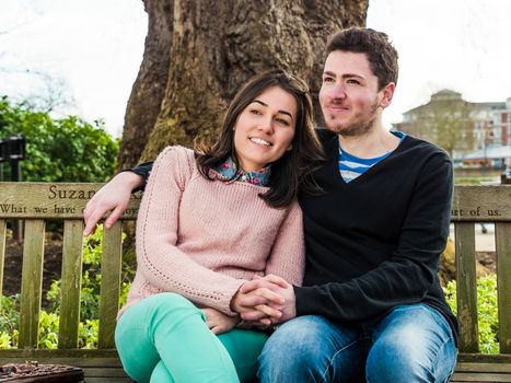 Portrait of Beautiful Young Couple Sitting on a Bench in a Park