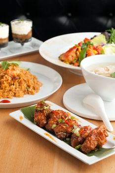 Varieties of Thai foods and appetizers covering a table. Shallow depth of field.