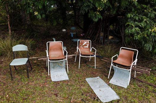 Abandoned chairs near children's makeshift hut in the woods.
