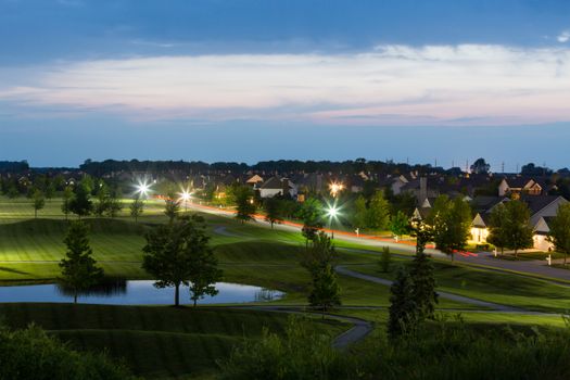 Overview of Luxury Neighborhood on Grounds of Golf Course at Dusk Illuminated by Street Lights