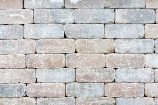 Background texture of a tumbled brick wall with aged variegated rectangular bricks with worn edges in a mortarless decorative construction