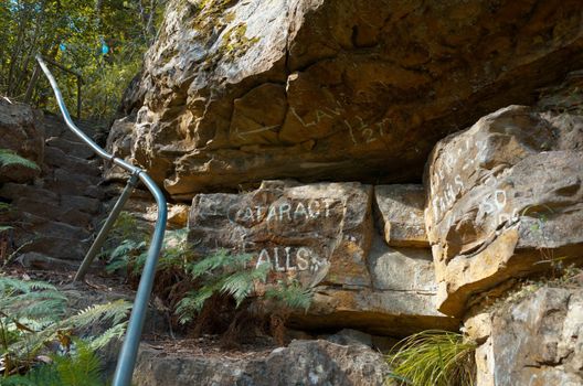 Stones steps on the side of a rock with painted direction signs in the Blue Mountains of Australia.