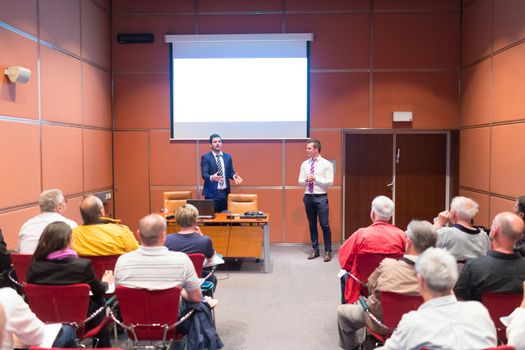 Speakers Giving a Talk at Business Meeting. Audience in the conference hall. Business and Entrepreneurship. Copy space on white board.