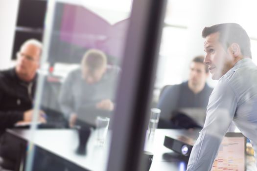 Business man making a presentation at office. Business executive delivering a presentation to his colleagues during meeting or in-house business training, explaining business plans to his employees.